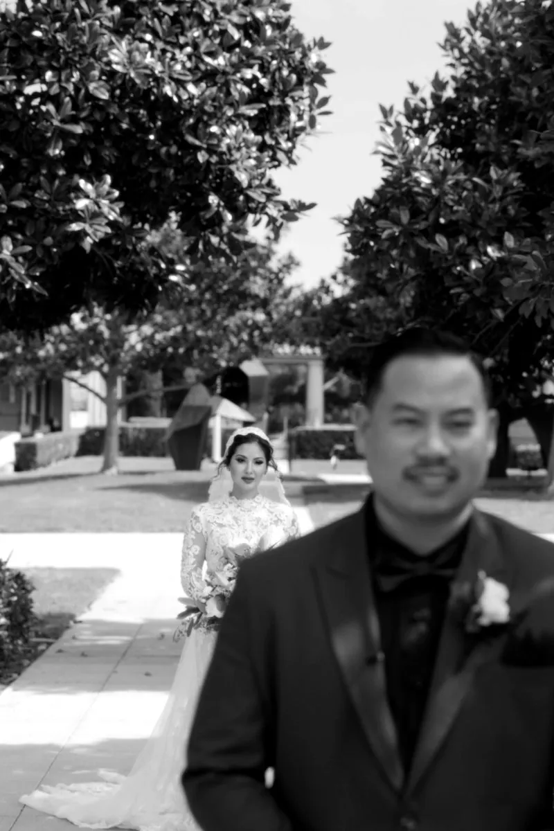 A groom waits with a smile as his bride approaches behind him