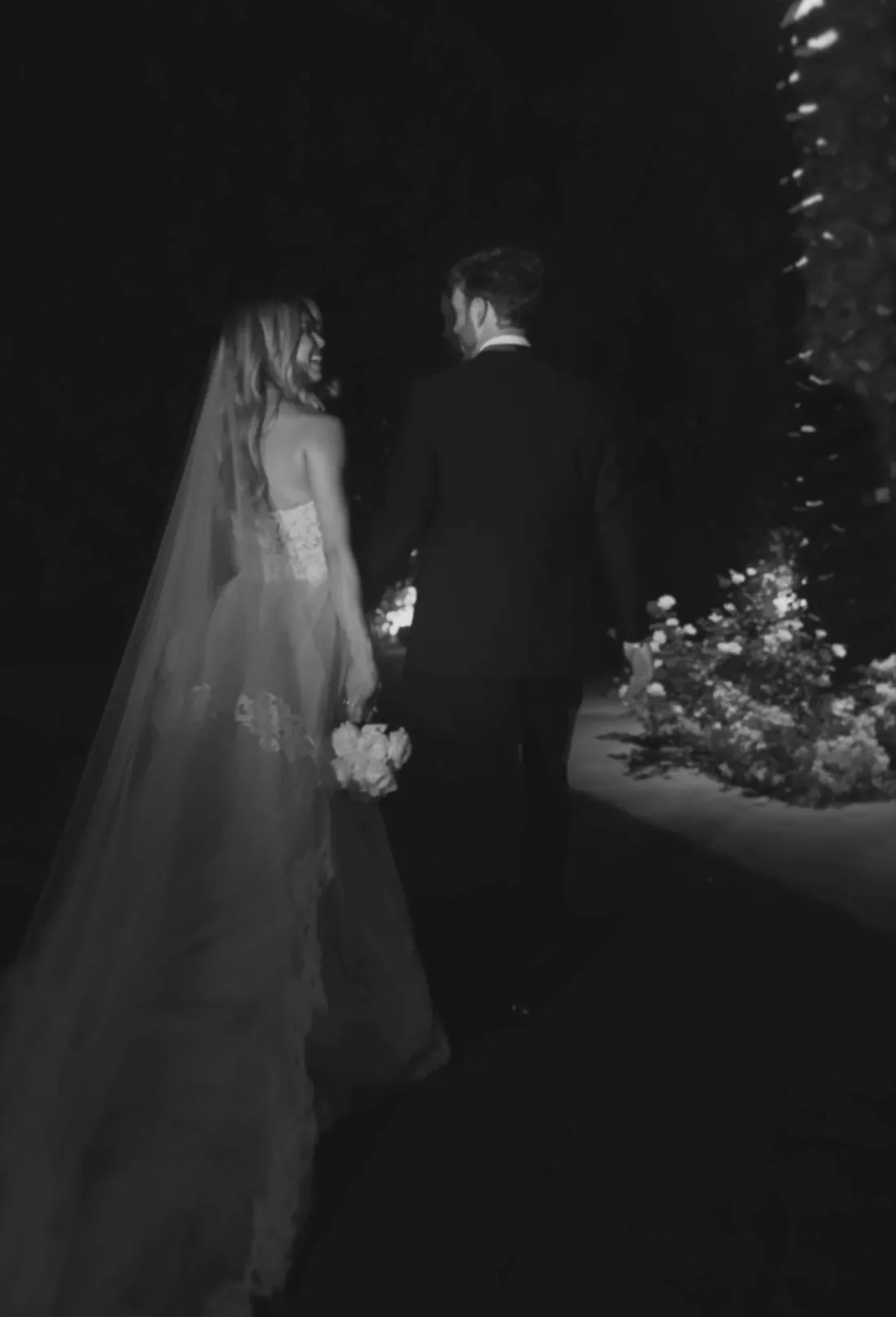 A bride and groom walk away together into the night